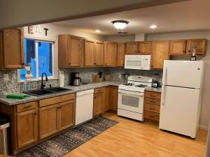 Una cocina con gabinetes de madera y un refrigerador blanco. en Cedar Oasis - Pet Friendly Cabin w Fireplace, Games and Wifi - 5 min to Big Trees, en Arnold