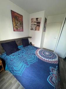 una camera da letto con un grande letto con una coperta blu di Chambre à Nanterre Proche Paris a Nanterre