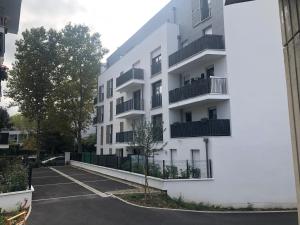 a white apartment building with a parking lot at Chambre double proche Arena La Defense in Nanterre