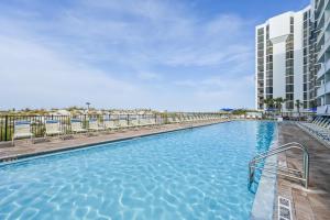 a swimming pool with chairs and a building at Pelican Beach Resort by Panhandle Getaways in Destin