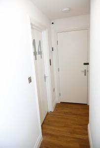pasillo vacío con puerta blanca y suelo de madera en London City Self Check-in Luxury Rooms en Londres