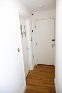 an empty hallway with a white door and wooden floors at London City Self Check-in Luxury Rooms in London