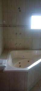a white bath tub in a bathroom with a light at Pousada Vale dos Sonhos - Suite Master com Hidromassagem in Capitólio