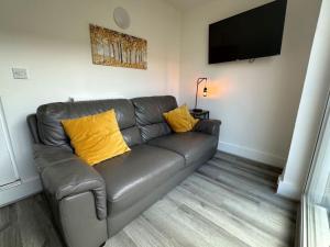 a leather couch with two yellow pillows in a living room at Carmen Sylva Llandudno Beach ground floor Flat in Llandudno