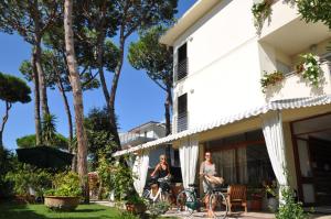 2 personnes sur la terrasse couverte d'une maison avec un chien dans l'établissement Hotel Etruria, à Forte dei Marmi