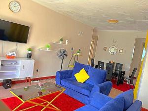 a living room with a blue couch and a tv at Homely apt 3 (three) in Kisumu