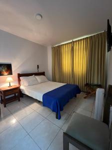 a bedroom with a large bed with a blue blanket at HOTEL ARMENIA CENTRO , TENEMOS AGUA CALIENTE y FACTURACION ELECTRONICA, Gracias in Armenia +39 photos
