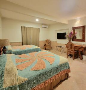 a hotel room with two beds and a television at Cabanas Maria Del Mar in Isla Mujeres
