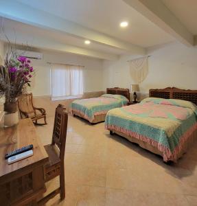 Un dormitorio con 2 camas y una mesa con flores. en Cabanas Maria Del Mar en Isla Mujeres