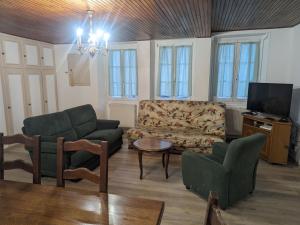 ein Wohnzimmer mit einem Sofa, Stühlen und einem TV in der Unterkunft Gîte Bourmont-entre-Meuse-et-Mouzon-Bourmont, 4 pièces, 6 personnes - FR-1-611-96 in Bourmont