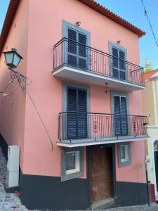 un bâtiment rose avec balcon et porte dans l'établissement Alojamento Príncipe D.Luís, à Ponta do Sol