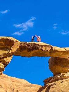 dos personas de pie en la parte superior de una formación rocosa en Wadi Rum albasli en Wadi Rum
