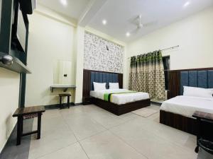 a hotel room with two beds and a television at Hotel Spiritual Land in Mathura