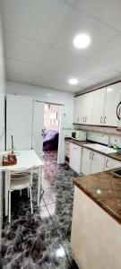 a kitchen with white cabinets and a table in it at Apartamento 1 línea de playa + Parking! Salou in Salou