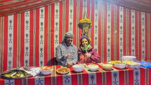 mężczyzna i kobieta siedzący przy stole z jedzeniem w obiekcie Wadi Rum albasli w mieście Wadi Rum