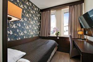 a hotel room with a bed and a desk and a computer at Brunnby Hotel in Stockholm