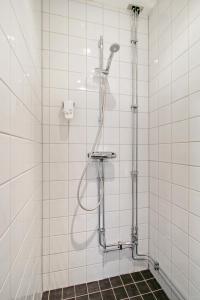 a shower in a white tiled bathroom at Brunnby Hotel in Stockholm