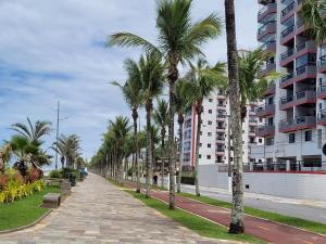 a sidewalk lined with palm trees next to a building at Apto completo - Solemar/PG in Praia Grande
