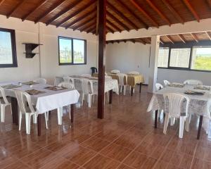 uma sala de jantar com mesas brancas e cadeiras brancas em Hotel Isla del descanso em Puerto Villamil