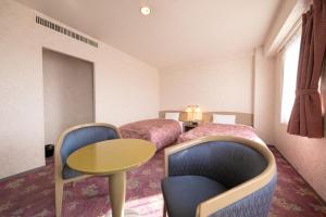 um quarto de hotel com duas camas e uma mesa e cadeiras em Main Hotel - Vacation STAY 85327v em Miyakonojo