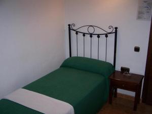 Un pequeño dormitorio con una cama verde y una mesa en Hostal Adrian en Pizarra