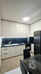 uma cozinha com armários brancos e um frigorífico preto em Kolo Apartament em Koło