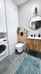 uma casa de banho com um WC, um lavatório e uma máquina de lavar roupa em Kolo Apartament em Koło