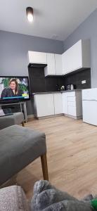 チェンストホヴァにあるKawalerka Centrum parking prywatnyの白いキャビネットと薄型テレビ付きのキッチンが備わります。