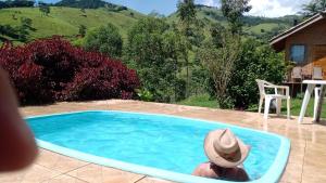 a person in a hat sitting in a swimming pool at Pousada Refugio Sol e Brisa in São Bento do Sapucaí