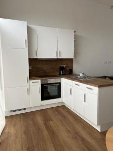 a white kitchen with white cabinets and a sink at Suite One Langestr II in Varel