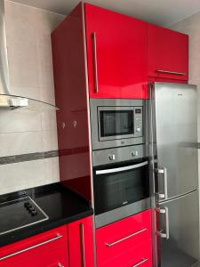 cocina con armarios rojos y microondas en Ocón 2, en Lebrija