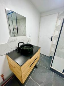 La salle de bains est pourvue d'un lavabo noir et d'un miroir. dans l'établissement Appartement Nicolas, à Aujac