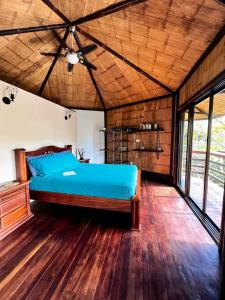 a bedroom with a blue bed and wooden floors at TREEHOUSE PILON PAVONES in Pavones