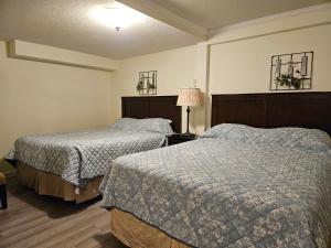 a bedroom with two beds and a lamp in it at Swiss Chalets Motel in Hope