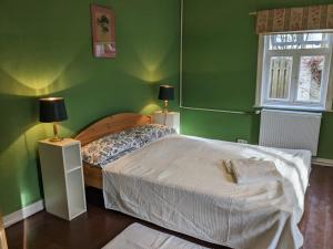 a green bedroom with a bed and two lamps at „Altes Forsthaus“ am Schloss in Uelzen