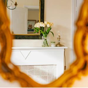 a mirror and a vase with white flowers on a mantle at Beach House in Whitley Bay
