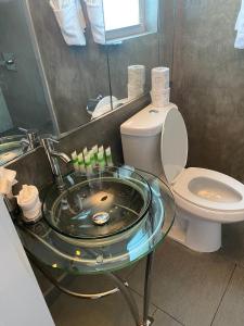 a bathroom with a glass sink and a toilet at M HOTEL in Miami Beach