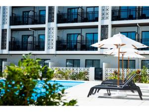 an umbrella and a bench in front of a building at Hotel Torifito Miyakojima Resort - Vacation STAY 79480v in Miyako Island