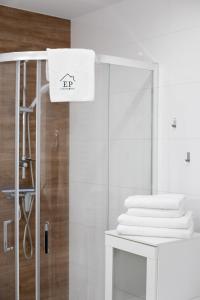 a white bathroom with a shower and a stack of towels at Apartament HAPPY 302 Łukęcin BlueMare EPapartamenty in Łukęcin