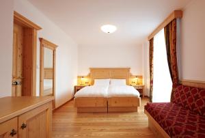 a bedroom with a bed and a red couch at Apparthotel Germania in Dobbiaco