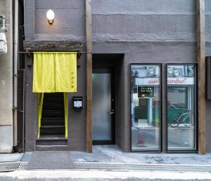 ein Gebäude mit gelbem Vorhang neben einer Tür in der Unterkunft Kobe Motomachi Roji Building - Vacation STAY 16195 in Kōbe