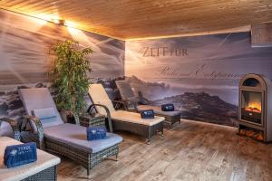 a room with a painting on the wall with chairs and a fireplace at Hotel Tyrol in Oberstaufen