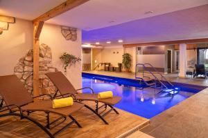 a pool in a house with chairs and a swimming pool at Hotel Tyrol in Oberstaufen