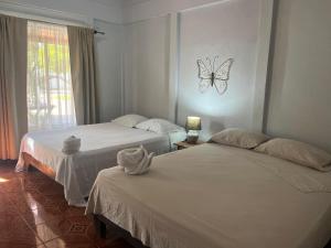 twee bedden in een kamer met een vlinder aan de muur bij Cabinas Bahía Uvita - Marino Ballena National Park Lodge in Uvita