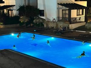 a group of people swimming in a pool at night at Nuramar Resort & Villas in Cala en Bosc