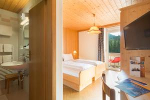 ein Schlafzimmer mit einem Bett, einem Waschbecken und einem Fenster in der Unterkunft Apparthotel Germania in Toblach