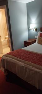 um quarto de hotel com uma cama e um candeeiro em The Emmbrook Inn Hotel em Wokingham