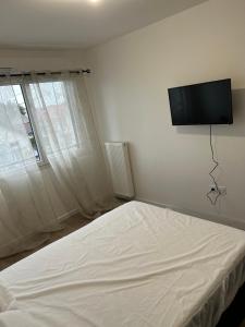 een slaapkamer met een bed en een flatscreen-tv aan de muur bij 2 bedrooms proche Paris/CDG/Bourget/Parc des expo in Le Blanc-Mesnil