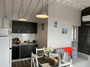 a kitchen with a table and chairs in a room at Cantinho dos Cagarros in Lajes do Pico