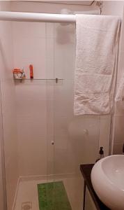 een badkamer met een douche, een wastafel en een handdoek bij Apartamento compartilhado quarto privativo in Foz do Iguaçu